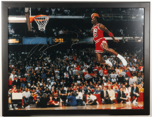 Michael Jordan airborne in a red Chicago Bulls uniform in a dark framed signed photograph